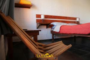 a room with two beds and a bench and a table at La Virazón in Punta Del Diablo
