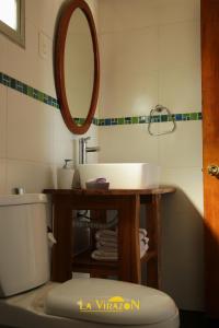 a bathroom with a sink and a mirror and a toilet at La Virazón in Punta Del Diablo