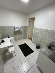 a kitchen with a sink and a microwave on the wall at Kitnets da Lane in Campos do Jordão