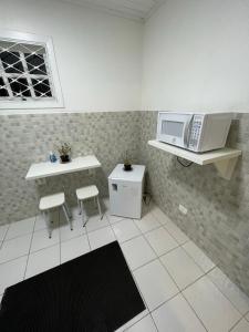a kitchen with a microwave and a table and chairs at Kitnets da Lane in Campos do Jordão