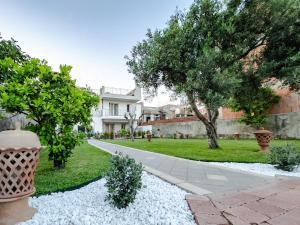 un jardin avec une maison, des arbres et du gravier dans l'établissement Ottocento Sul Mare, à Nizza di Sicilia