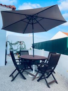 stół i dwa krzesła z parasolem w obiekcie Casa do Canto - Uma casa no campo, perto da praia. w mieście Óbidos