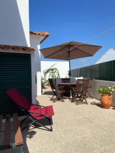 un patio con mesa, sillas y sombrilla en Casa do Canto - Uma casa no campo, perto da praia., en Óbidos