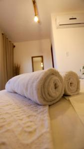 a bed with two rolled towels on top of it at Pousada Movimento in Prea