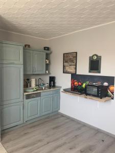 a kitchen with blue cabinets and a sink and a microwave at Ferien-Landleben in Löbnitz +13 photos