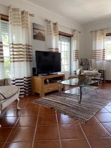 a living room with a television and a table at Casa do Canto - Uma casa no campo, perto da praia. in Óbidos