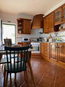 una cocina con armarios de madera y una mesa con sillas. en Casa do Canto - Uma casa no campo, perto da praia., en Óbidos