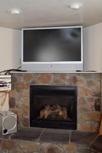 TV de pantalla plana encima de una chimenea de piedra en Sleepy J Cabins, en Swan Valley