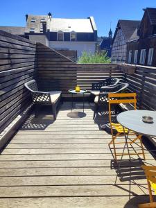 a wooden deck with tables and chairs on it at Le cosy 40 - maison typique au centre de Malmedy in Malmedy