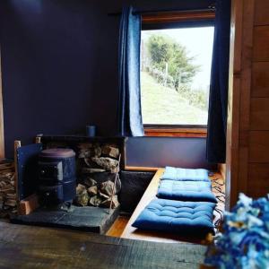 a room with a stove and a window with blue curtains at Casa de campo Jaulares in Alaska