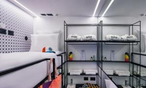 Zimmer mit einem Bett und Regalen mit Handtüchern in der Unterkunft WOM Beach POD Hotel -By WOM POD Chain in Tel Aviv