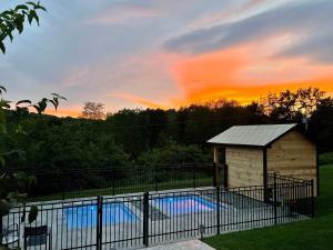 a swimming pool in a fence with the sunset in the background at Auberge Le Tricorne in North Hatley