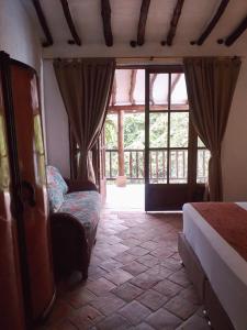 1 dormitorio con 1 cama, 1 silla y 1 ventana en Casona CHARA, en Barichara
