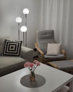 uma sala de estar com um vaso de flores sobre uma mesa em BAM apartments em Palanga