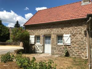 una antigua casa de piedra con techo rojo en Gîtes Le Fer A Cheval Vassivière en Royère-de-Vassivière