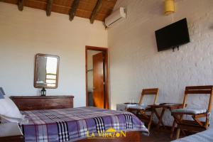 um quarto com uma cama e uma televisão na parede em La Virazón em Punta Del Diablo