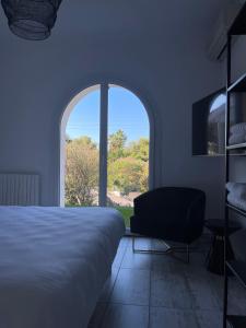 ein Schlafzimmer mit einem Bett, einem Stuhl und einem Fenster in der Unterkunft VILLA LA QUIETUDE in Les Issambres