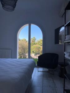 sypialnia z łóżkiem, krzesłem i oknem w obiekcie VILLA LA QUIETUDE w mieście Les Issambres