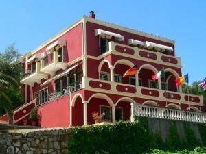 a red building with flags in front of it at Room in BB - The Quality And Hospitalityof Apraos Bay Hotel Has Been Identified in Apraos