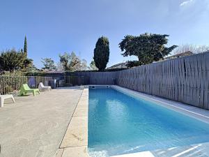 a swimming pool in a backyard with a fence at La Fontaine aux Poissons Rouges in Moussac
