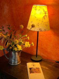 a lamp sitting on a table next to a vase with flowers at Barco Mediceo B&B In Toscana in Carmignano