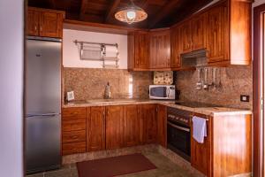 uma cozinha com armários de madeira e um frigorífico de aço inoxidável em Casa Rural La Palizada em Benchijigua