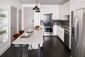 a kitchen with white cabinets and a large island with bar stools at Sentral East Austin at 1614 E Sixth in Austin