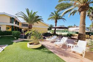 un patio con sillas blancas y palmeras en Villa Maspalomas Golf Court, en Maspalomas