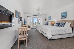 a bedroom with two beds and a table and a fireplace at Beach House Inn & Suites in Pismo Beach