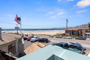Blick auf den Strand mit Autos auf einem Parkplatz in der Unterkunft Beach House Inn & Suites in Pismo Beach