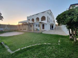 a large white house with a large yard at La riva in Noto Marina