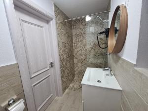 a white bathroom with a sink and a mirror at URBANIST Guest House in Călimăneşti