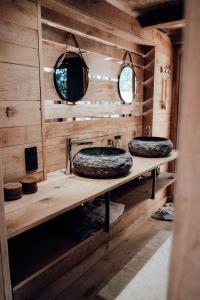 two sinks in a bathroom with wooden walls and mirrors at The WoodPecker Lodge in Waimes