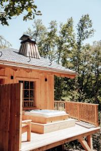 Cabaña de madera con terraza con bañera de hidromasaje en The WoodPecker Lodge, en Waimes