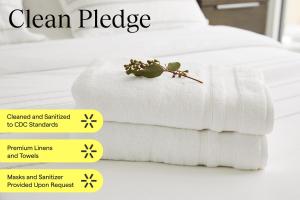 uma pilha de toalhas brancas numa cama com placas amarelas em Sentral East Austin at 1630 E Sixth em Austin