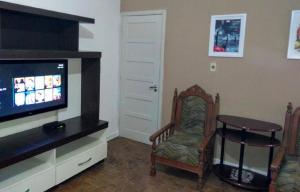 a living room with a tv and a chair and a table at Apartamento Primeira Quadra Da Praia in Praia Grande