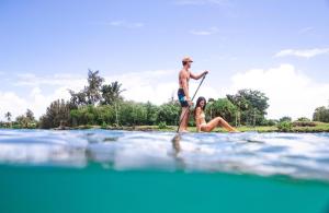 un hombre y una mujer en una tabla de surf de remo en el agua en Stunning Views Best location in Hilo 2BR modern Condo en Hilo