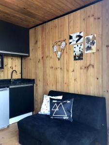 a living room with a black couch and wooden walls at Modo- lar mini casa in Penha