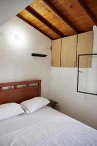 Un dormitorio con una cama con sábanas blancas y techos de madera. en Hotel Gran Girones en Girón