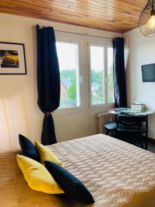 Un dormitorio con una cama con almohadas amarillas y una ventana en Studio COSY avec parking et wifi gratuit, en Bagnoles de l'Orne
