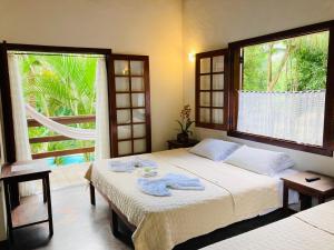 a bedroom with two beds and a large window at Pousada Rumo dos Ventos in Paraty