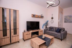 a living room with a couch and a flat screen tv at Zoes Luxury Apartment Corfu in Ágios Rókkos