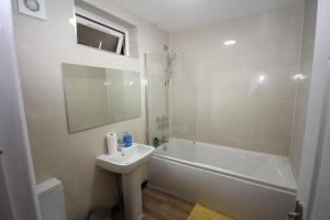 a bathroom with a sink and a tub and a toilet at The Heathrow House in Cranford