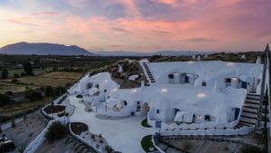- une vue aérienne sur un grand bâtiment blanc avec un coucher de soleil dans l'établissement Complejo Cuevas Otto, à Baza