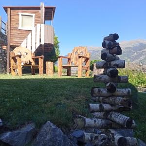 a stack of logs in the grass next to a log cabin at MAISON BLANC in Aymavilles