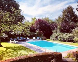 a swimming pool in a garden with lounge chairs at Le Clos Margaux in Chaudfontaine