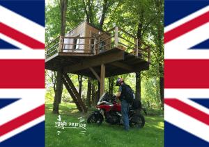 a man standing next to a motorcycle in front of a tree house at Medže Dirbtuve in Kalnelis