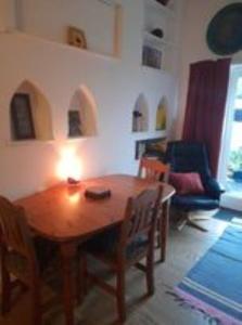 una sala de estar con mesa de madera y una habitación con sofá en Janet Hale Studios, Garden Apartment, en Glastonbury