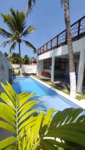 - une piscine en face d'une maison avec des palmiers dans l'établissement Casa Morica! Casa nova com Piscina!, à Icaraí