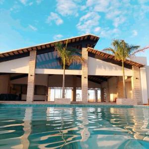 a building with palm trees and a swimming pool at Complexo Alpes do Cerrado in Sobradinho